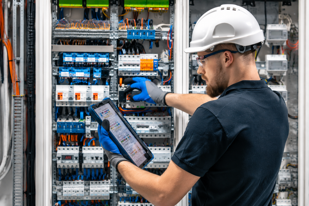 Elektriker führt einen E-Check am Schaltschrank durch Elektriker führt einen E-Check am Schaltschrank durch